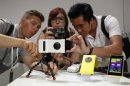 Guests at Nokia's unveiling of its new Lumia 1020 smartphone use the new phone's 41-megapixel camera with a grip in New York