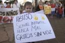 A child holds a sign that reads in Spanish "Sexual child abuse never again, screams without voice," at a demonstration in front of the Attorney General's office in Ciudad del Este, Paraguay, Monday, May 11, 2015. Paraguayans have debated what should happen to a 10-year-old pregnant girl who was raped. The girl's mother has asked for an abortion, but health officials have ruled it out. The stepfather who raped the girl has been arrested. (AP Photo/Peter Prengaman)