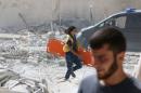 A man runs with a stretcher in a damaged site after airstrikes on the rebel held al-Qaterji neighbourhood of Aleppo