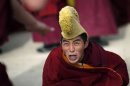 A monk reacts as he participates in a debate as part of Tibetan New Year celebrations at a temple in Langmusixiang