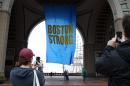 People photograph a banner reading "Boston Strong" hanging at Rowes Wharf on the first anniversary of the Boston Marathon bombings on Tuesday, April 15, 2014, in Boston. (AP Photo/Bill Sikes)