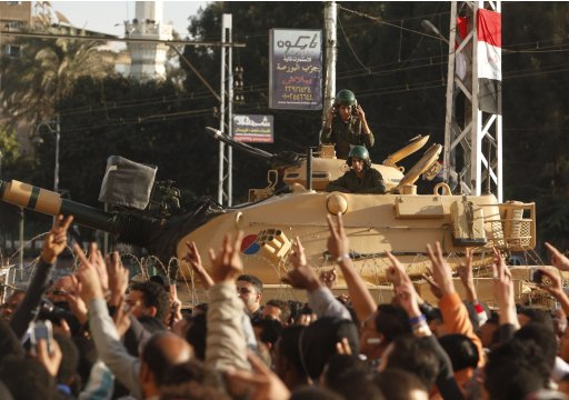 Protesters chant slogans against Egypt's President Mursi in front of a barbed wire barricade guarded by a tank outside the presidential palace in Cairo