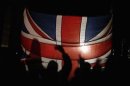 Falkland islanders are silhouetted behind the Union Jack as they react after hearing the results of the referendum in Stanley