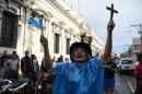 A man celebrates with a cross and a national flag after the Congress voted unanimously to strip embattled President Otto Perez's immunity in Guatemala City on September 1, 2015