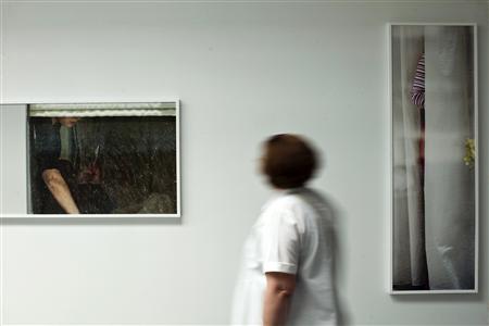 A woman attends a photo exhibition called "The Neighbors" by fine art photographer Arne Svenson at Julie Saul Gallery in New York in this June 1, 2013 file photo. Svenson, who secretly used a zoom lens to photograph his neighbors napping and eating has caused a citywide stir -- and two legal actions so far. REUTERS/Eduardo Munoz/Files