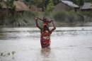 A woman carries her child as she wades through floodwaters at a flooded village in Gaibandha