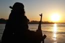 In this photo released on Sept. 29, 2014 by a militant website, which has been verified and is consistent with other AP reporting, an Islamic State group fighter holds his AK-47 machine gun as he relaxes on the bank of the Euphrates river in Raqqa, Syria. The IS group has set up a generous welfare system to help settle and create lives for the thousands of jihadis, men and women, who have flocked to IS territory from the Arab world, Europe, Central Asia and the United States. (Militant website via AP)