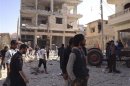 Residents walk on rubble near buildings which are damaged after a Syrian Air Force fighter jet loyal to Syria's President Bashar al-Assad fired missiles at Binsh