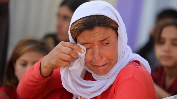 A displaced Iraqi Yazidi woman wipes her eyes at the Bajid Kandala camp near the Tigris River, in Kurdistan's western Dohuk province, where they took refuge after fleeing advances by Islamic State jihadists in Iraq on August 13, 2014