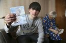 In this photo taken on Saturday, March 20, 2013, Alexander Abnosov shows his American passport to journalists in the Volga river city of Cheboksary, Russia. His 72 -years old grandmother is in the background. Abnosov was adopted by an American couple at age 12 has returned to Russia claiming that his parents treated him badly, according to reports from Russian media with close ties to the Kremlin. (AP Photo/Nikolay Alexandrov)