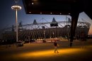 A volunteer walks past the Olympic Stadium at the 2012 Summer Olympics, Sunday, July 22, 2012, in London. The opening ceremonies of the Olympic Games are scheduled for Friday, July 27. (AP Photo/Emilio Morenatti)