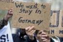 People hold signs during a pro-refugee demonstration in downtown Hamburg, Germany