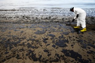 A worker removes oil from sand at Refugio State Beach, north of Goleta, Calif. (AP/Jae C. Hong)