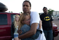 Judy Goos, center left, hugs her daughter's friend, Isaiah Bow, 20, while eyewitnesses Emma Goos, 19, left, and Terrell Wallin, 20, right, gather outside Gateway High School where witnesses were brought for questioning Friday, July 20, 2012, in Aurora, Colo. A gunman wearing a gas mask set off an unknown gas and fired into a crowded movie theater at a midnight opening of the Batman movie "The Dark Knight Rises," killing at least 12 people and injuring at least 50 others, authorities said. (AP Photo/Barry Gutierrez)