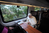 In this photo provided by the Vatican newspaper Osservatore Romano, Pope Benedict XVI, right, reads as he travels for a meeting in Assisi, central Italy, Thursday, Oct. 27, 2011. Buddhist monks, Muslim imams, Orthodox patriarchs and Yoruba leaders have flocked with Pope Benedict XVI to the Umbrian hilltown of Assisi to make an interfaith call for peace and insist that religion must never be used as a pretext for war. (AP Photo/Osservatore Romano) EDITORIAL USE ONLY
