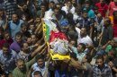 Mourners carry the bodies of one of three Palestinians killed in Qalandiya refugee camp, August 26, 2013