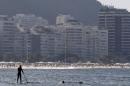 A man paddles on a stand up board on Copacabana beach in Rio de Janeiro