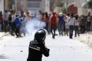 A riot police officer fires teargas during clashes with supporters of Islamist group Ansar al-Sharia at Hai al Tadamon in Tunis