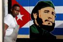 An employee of a state-owned candy store looks outside, near a painting depicting Cuba's former President Fidel Castro, following the announcement of Castro's death, in Havana