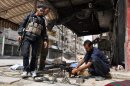 A rebel fighter cleans his weapon as two of his comrades look on in the northern city of Aleppo on September 20, 2013