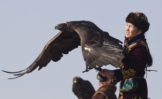 A hunter releases her tame golden eagle during an annual hunting competition outside Almaty