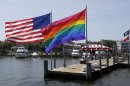In this June 23, 2013 photo, an American flag and a LGBT Rainbow flag are displayed on the ferry dock in the Fire Island community of Cherry Grove, N.Y. The 1969 Stonewall uprising in New York City is generally accepted as the Lexington and Concord of the gay rights revolution - the first shots in a battle that eventually led to last week's landmark Supreme Court decision legalizing gay marriage. But in this seaside resort 60 miles east of Manhattan, reports that homosexuals were standing up for their rights that summer of Woodstock and moon landings was hardly breaking news: a gay community in Cherry Grove had been thriving there for at least two decades before Stonewall. (AP Photo/Seth Wenig)