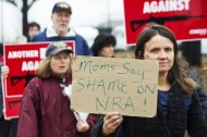 Protestors hold up signs as they descend on the office of a lobbyist for the National Rifle Association in Washington on December 17, 2012. The powerful US gun lobby has turned silent on social media, apparently suspending its Facebook page, after last week's school massacre that took the lives of 20 small children and six adults
