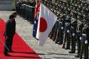 Australia's PM Abbott bows to Australian and Japanese national flags as he reviews a guard of honour with Japan's PM Abe during a welcome ceremony in Tokyo