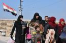 A Syrian family arrives at a checkpoint, manned by pro-government forces, at the al-Hawoz street roundabout, after leaving Aleppo's eastern neighbourhoods