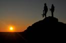 People's Protection Units (YPG) fighters stand on a hill at sunset on February 26, 2015, after they retook parts of the town of Tal Hamis, southeast of the city of Qameshli, after six days of clashes with Islamic State (IS) group jihadists