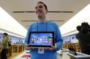 FILE - In this Friday, Oct. 26, 2012, file photo, Microsoft store product advisor Stuart Pitts displays the new Surface tablet computer as customers enter the store as it opened in Seattle. The Surface is Microsoft's first attempt at a general-purpose computer. In the past, it made the software and left it to other companies to make the machines. But to catch the tablet wave led by Apple's iPad, Microsoft felt it needed to make its own device. (AP Photo/Elaine Thompson, File)