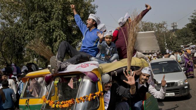 FILE- In this, Feb. 14, 2015 file photo, supporters of the Aam Aadmi Party (AAP), or Common Man’s Party, shout slogans as they sit on an autorickshaw decorated with brooms, the party symbol, outside the venue where party leader Arvind Kejriwal is being sworn-in as the new chief minister of Delhi, in New Delhi, India. The upstart AAP, was once seen by many as a breath of fresh air in the chaotic, corruption-tainted world of Indian politics, promising to root out graft and display complete transparency. Now, however, with its top leaders spending the weekend slugging it out in public, it seems the party that promised to transform India's political landscape is more likely to bring disappointment to millions of Indians despairing of their politicians.. (AP Photo/Bernat Armangue, file)