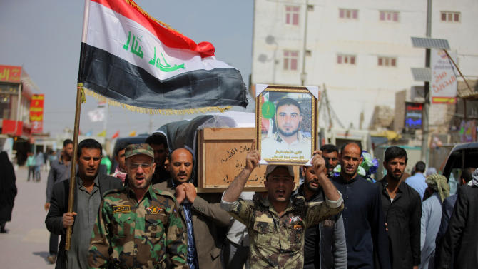 Members of an Iraqi Shiite militant group called Badr Brigades carry the coffin of  Shiite fighter, Mohammed Fuad, and a poster with his picture, during his funeral procession in the Shiite holy city of Najaf, 100 miles (160 kilometers) south of Baghdad, Iraq, Monday, March 9, 2015. Fuad was killed in Tikrit fighting Islamic State militants, his comrades said. (AP Photo/Jaber al-Helo)