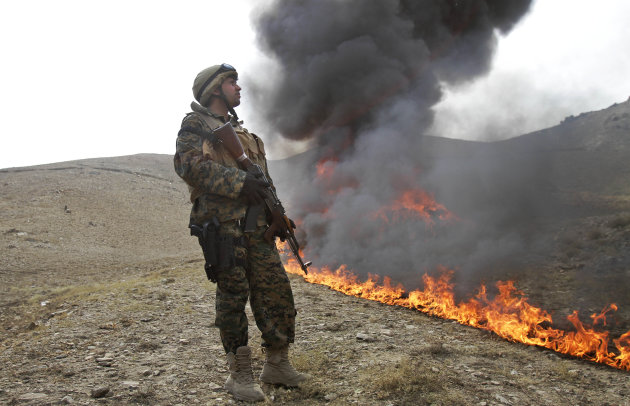 An Afghan counternarcotic policeman (CNPA) secures the area as 25 tons of drugs and drug-making gear are burned on the outskirts of Kabul, Afghanistan, Sunday, Oct. 14, 2012. The 25 tons of drugs and paraphernalia where confiscated over the past nine months in the Kabul area. (AP Photo/Ahmad Jamshid)