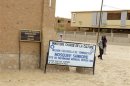 People walk past signs marking heritage sites in Timbuktu
