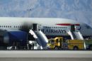 Firefighters stand by a plane that caught fire at McCarren International Airport, Tuesday, Sept. 8, 2015, in Las Vegas. An engine on the British Airways plane caught fire before takeoff, forcing passengers to escape on emergency slides. (AP Photo/John Locher)