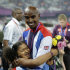 Great Britain's Mohamed Farah shows off his gold medal to his stepdaughter Rihnna after the awards ceremony for the men's 5000-meter during the athletics in the Olympic Stadium at the 2012 Summer Olympics, London, Saturday, Aug. 11, 2012. (AP Photo/Matt Slocum)