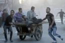 Two injured men are transported on a fruit barrow in the Syrian city of Aleppo, following shelling as fighting between pro-government forces and rebels continues on October 26, 2013