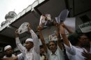 Muslim men hold up pictures of recent violence in Rakhine state at a protest