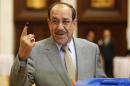 Nuri al-Maliki shows his ink marked finger as he votes during parliamentary election in Baghdad