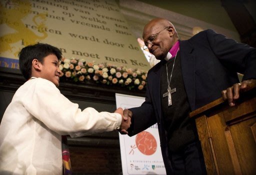 Desmond Tutu (R) shakes hands with Cris "Kesz" Valdez after awarding him with the Children's Peace Prize