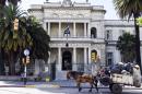 A horse cart passes by the military hospital in Montevideo, Uruguay, Sunday, Dec. 7, 2014. Six prisoners from Guantanamo Bay have been transferred to Uruguay, the U.S. government said Sunday. Uruguayan officials declined comment on the transfers but Adriana Ramos, a receptionist at the hospital, said the six men were being examined there. (AP Photo/Matilde Campodonico)