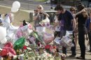 Actor Christian Bale, second right, and his wife Sibi Blazic, right, place flowers on a memorial to the victims of Friday's mass shooting, Tuesday, July 24, 2012, in Aurora, Colo. Twelve people were killed when a gunman opened fire during a late-night showing of the movie Dark Knight Rises, which stars Bale as Batman. (AP Photo/Ted S. Warren)