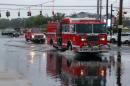 Firefighters cross a flooded intersection on Route 110 in Farmingdale, N.Y., on New York's Long Island, Wednesday, Aug. 13, 2014. Stranded Long Island drivers have been rescued after a storm slammed Islip, N.Y., with over 12 inches of rain — an entire summer's worth. (AP Photo/Frank Eltman)