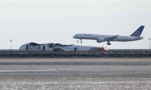 An aircraft lands behind the wreckage of the Asiana Airlines plane at San Francisco International Airport in San Francisco
