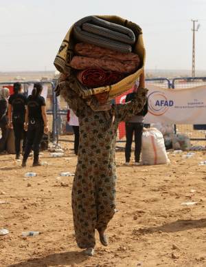 A Syrian refugee from Kobani carries her belongings …