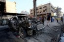 Iraqi men inspect the wreckage of a car at the site of a car bomb explosion in central Baghdad on September 18, 2013