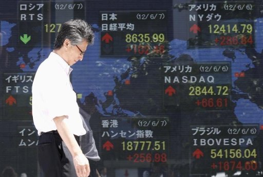 A man walks past a stock index board outside a brokerage in Tokyo