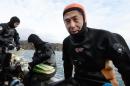 Yasuo Takamatsu (R) speaks to an AFP reporter beside his instructors as he sits on the edge of a boat after diving in the ice-cold sea water in Onagawa, Miyagi Prefecture, on March 2, 2014