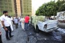 People look at a vehicle belonging to the Libyan army after it exploded in Benghazi